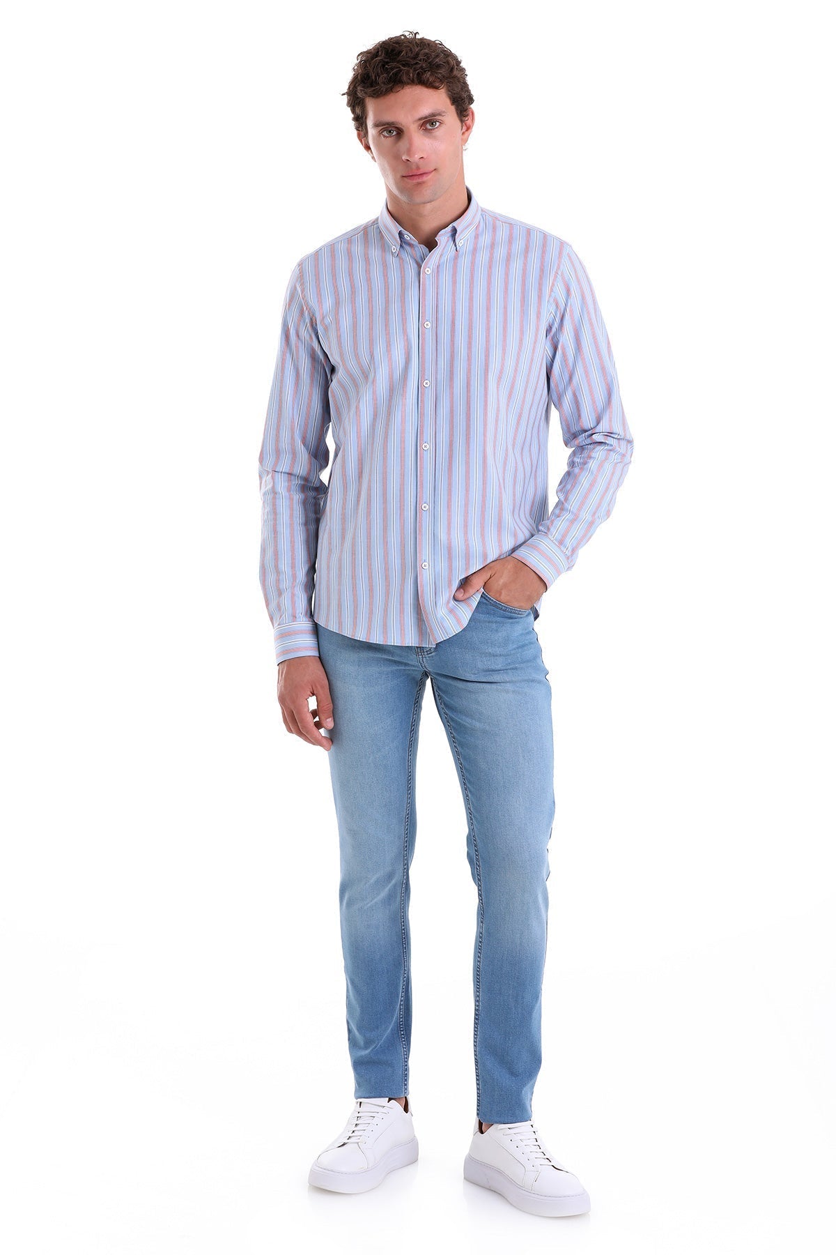 A man wearing a light blue and white striped long-sleeved button-down shirt paired with medium-wash denim jeans.