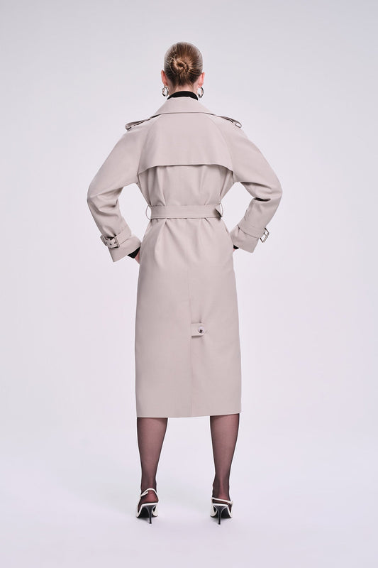 Beige trench coat with a belted waist, structured shoulders, and silver-toned hardware.