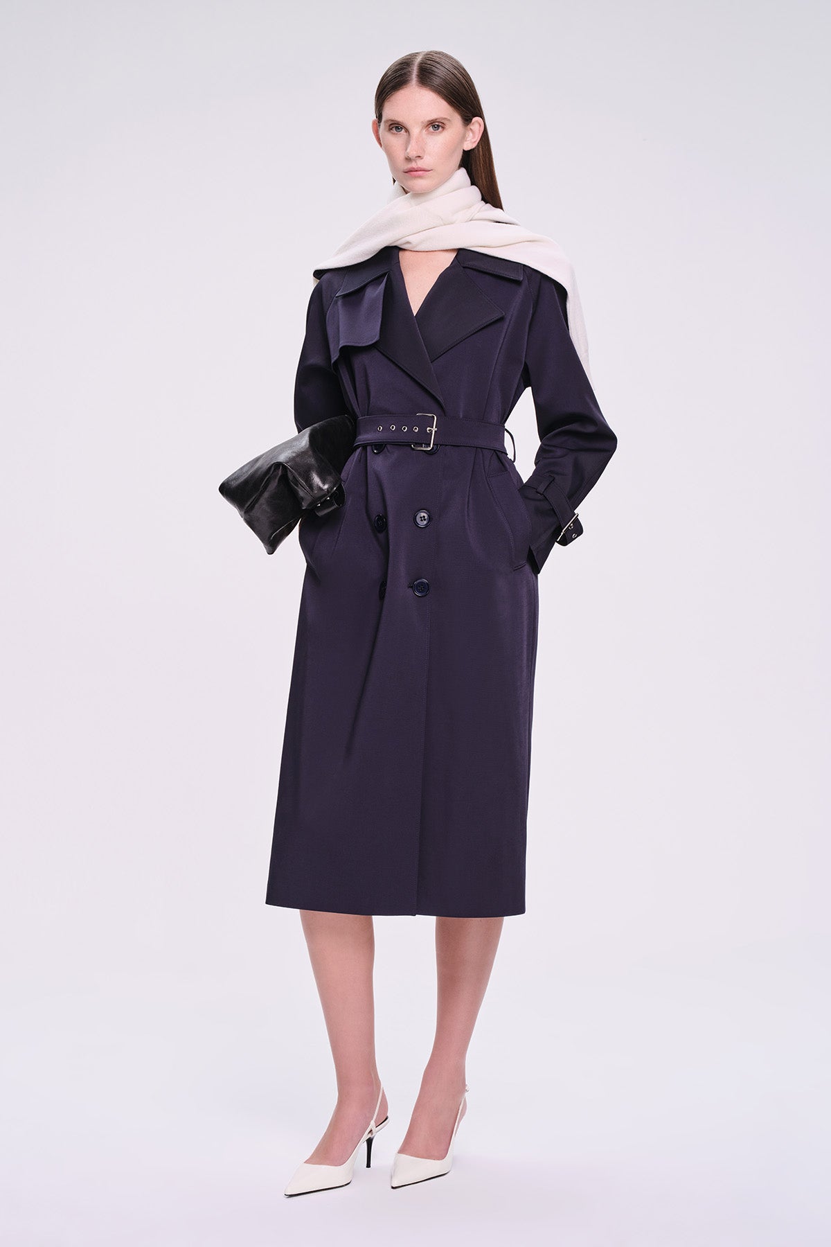 A sleek navy blue trench coat with a belted waist, double-breasted front, and structured shoulders.