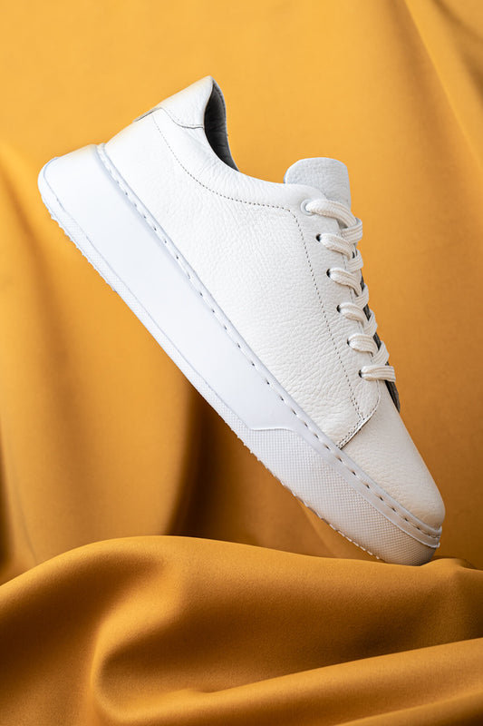 White leather sneaker with a clean, minimalist design and matching white laces.