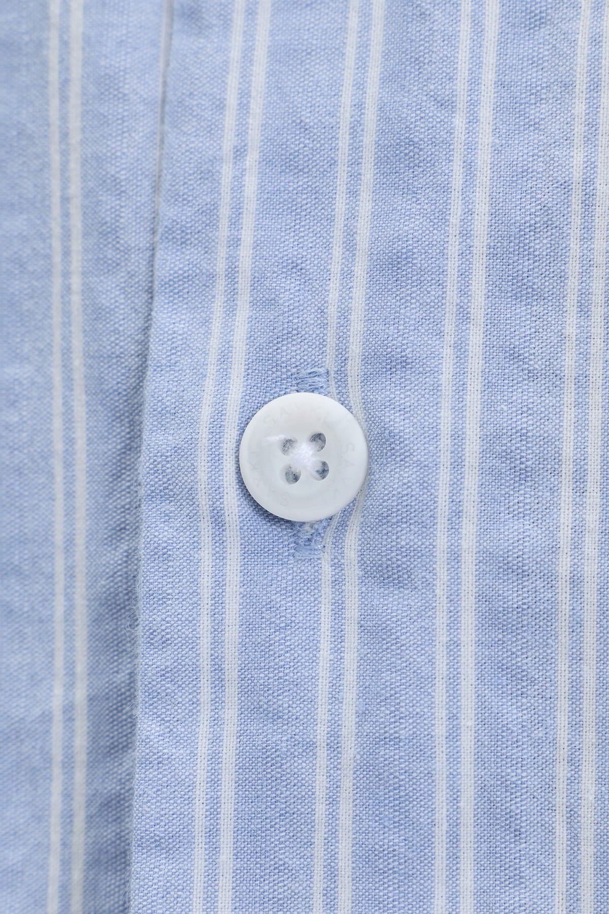 A white four-hole button on a comfort fit blue striped cotton smart casual shirt with vertical stripes