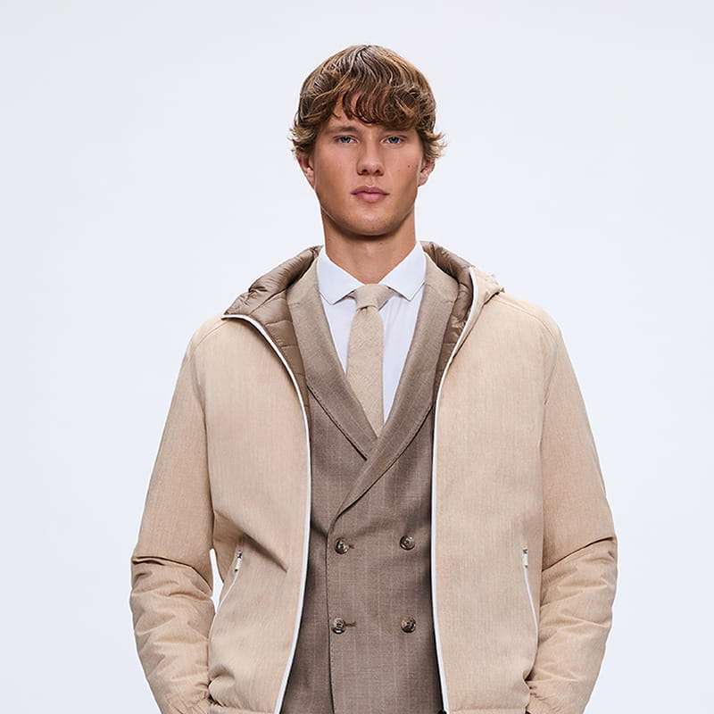 Man wearing light beige padded jacket over tailored suit, refined winter gift style