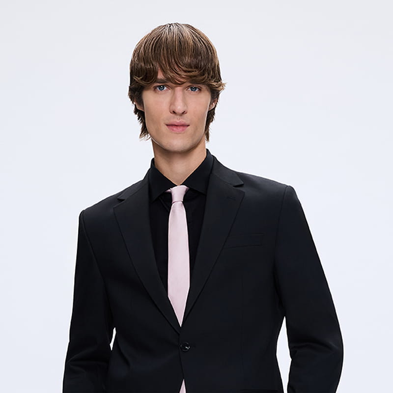 Man wearing black suit with light-colored tie, formal menswear gift category