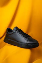Black leather low-top sneaker with a textured surface and matching laces.