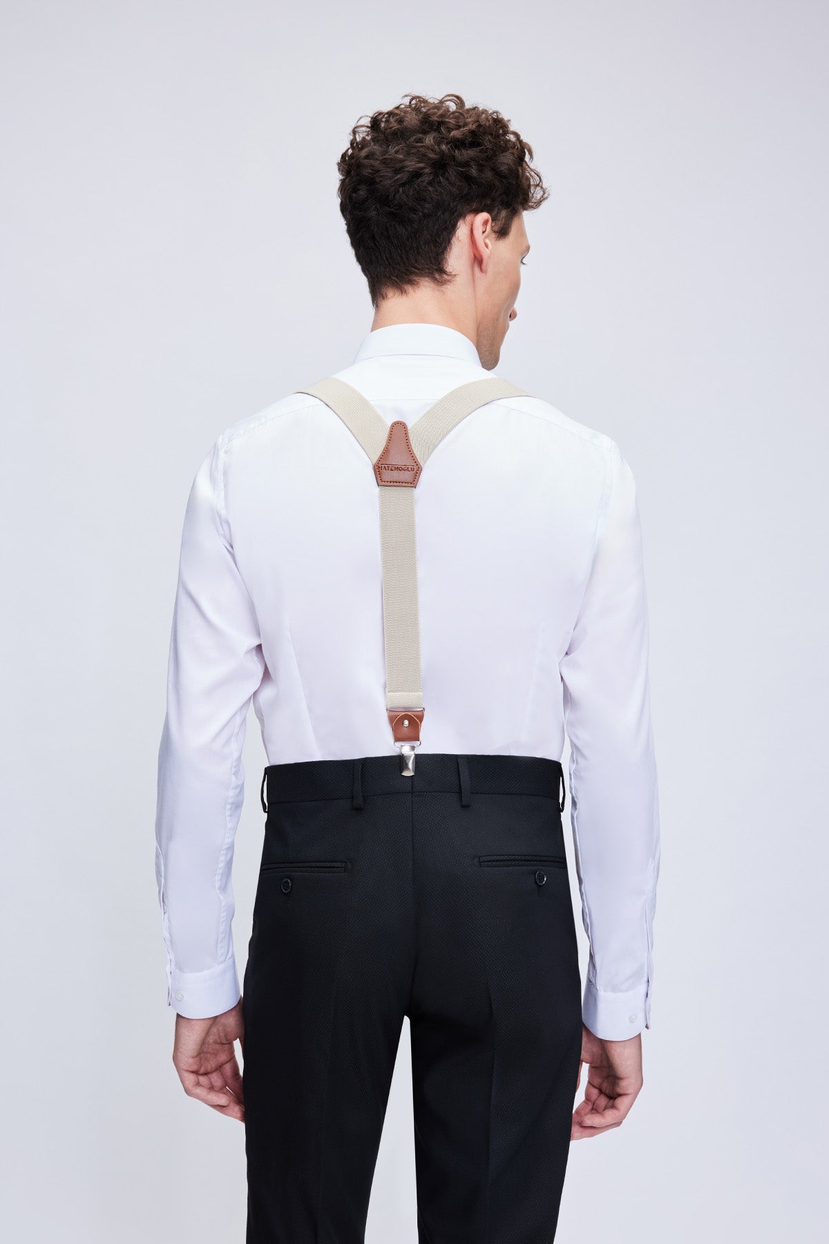 Beige leather trim clip suspenders with elastic straps, brown leather clasps, and subtle logo on the back strap