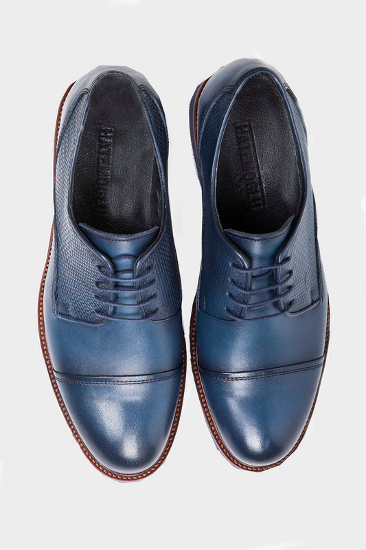 Navy blue leather dress shoes with a contrasting textured panel on the side and brown stitching along the sole
