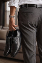 A pair of sleek black leather cap toe derby shoes with polished finish and classic lace up design
