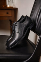Black lace up 100 percent leather cap toe derby shoes with sleek polished finish and classic lacing design