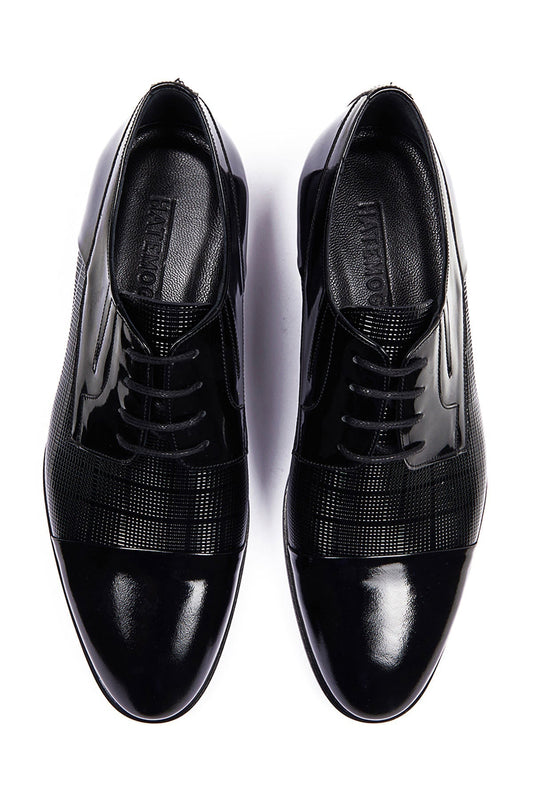 Black patent leather dress shoes with a glossy finish and textured paneling on the sides.