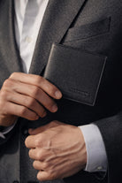 Black wallet made of genuine leather black with textured finish and embossed brand logo on the front
