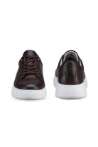 Brown leather sneakers with white rubber soles and matching brown laces.