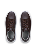 Brown leather sneakers with white soles and matching laces.