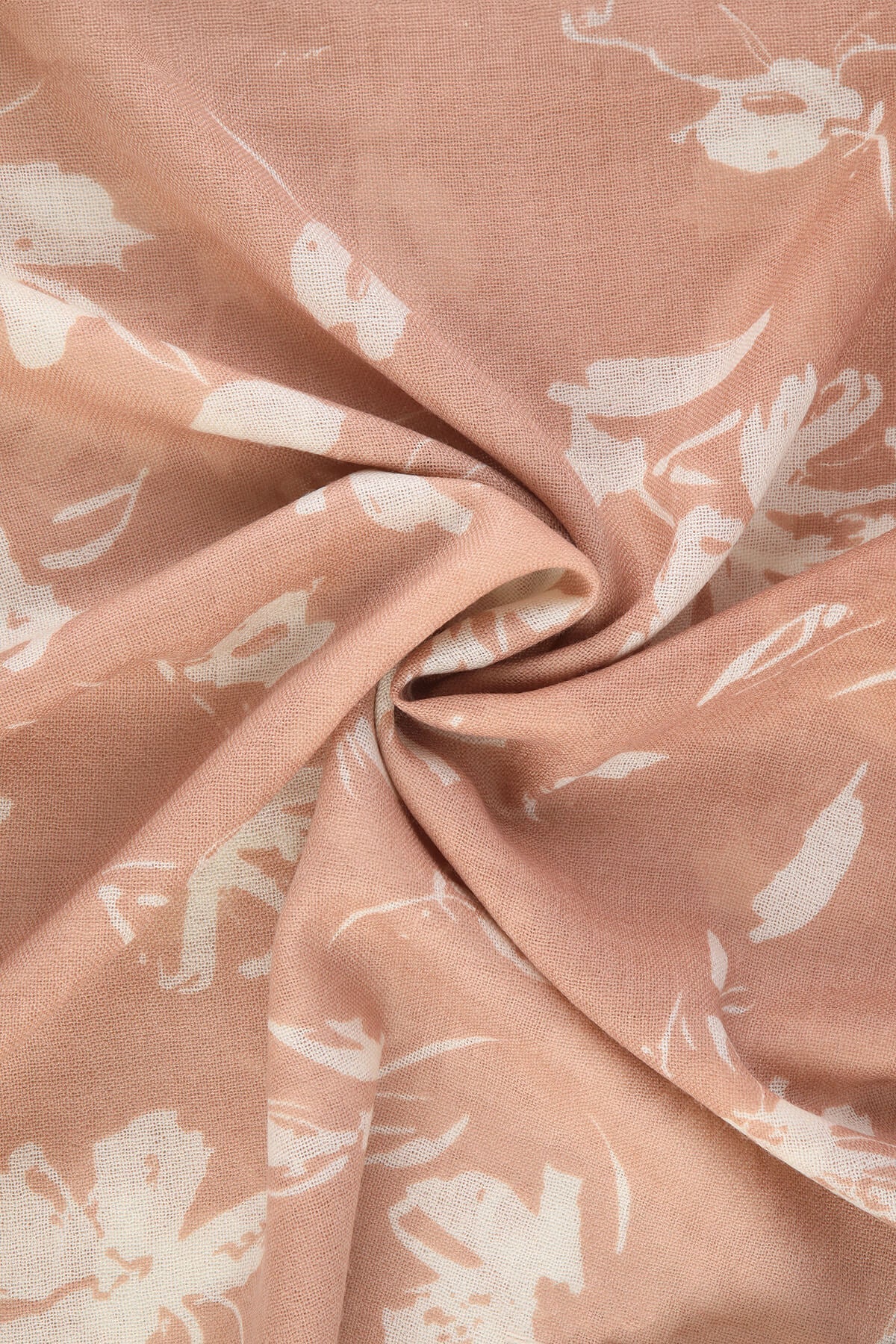 A soft peach-colored scarf with a delicate white floral pattern, made of lightweight fabric.