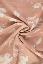 A soft peach-colored scarf with a delicate white floral pattern, made of lightweight fabric.