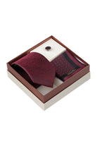 A burgundy textured silk tie with subtle pattern neatly folded in an elegant gift box with pocket square and lapel pin
