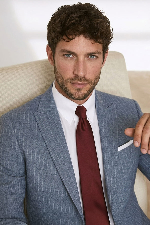 A man wearing a blue pinstripe suit jacket with a white dress shirt and a casual 2.36 inches burgundy tie