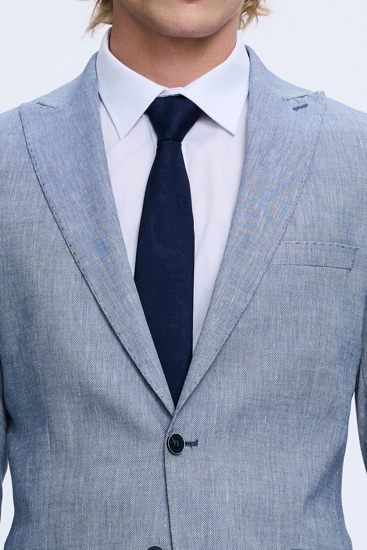 Light blue textured blazer with notched lapel and single-breasted design paired with inches solid navy tie