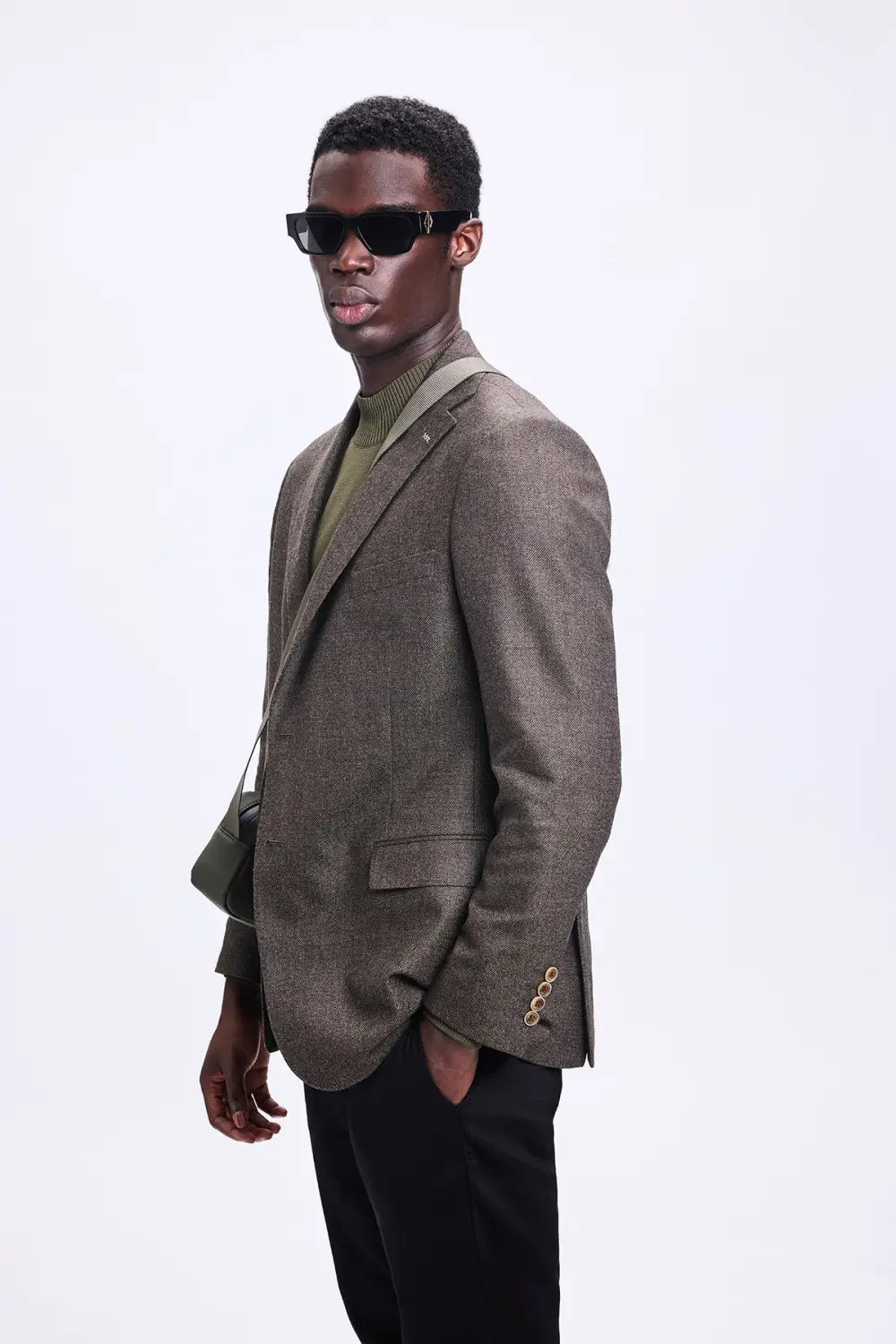 Model in navy blazer with black t-shirt and silver chain necklace demonstrating casual formal styling