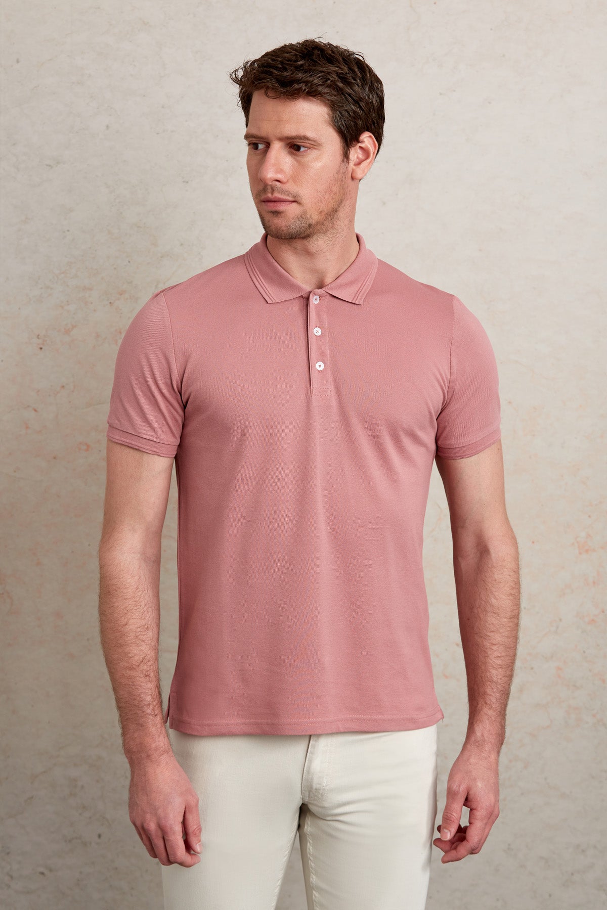 A soft pink short-sleeved polo shirt with a classic collar and white buttons.