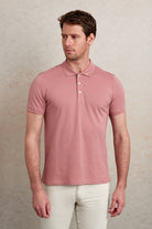 A soft pink short-sleeved polo shirt with a classic collar and white buttons.