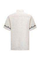 Off-white linen short-sleeved shirt with intricate black and blue embroidered patterns along the cuffs.