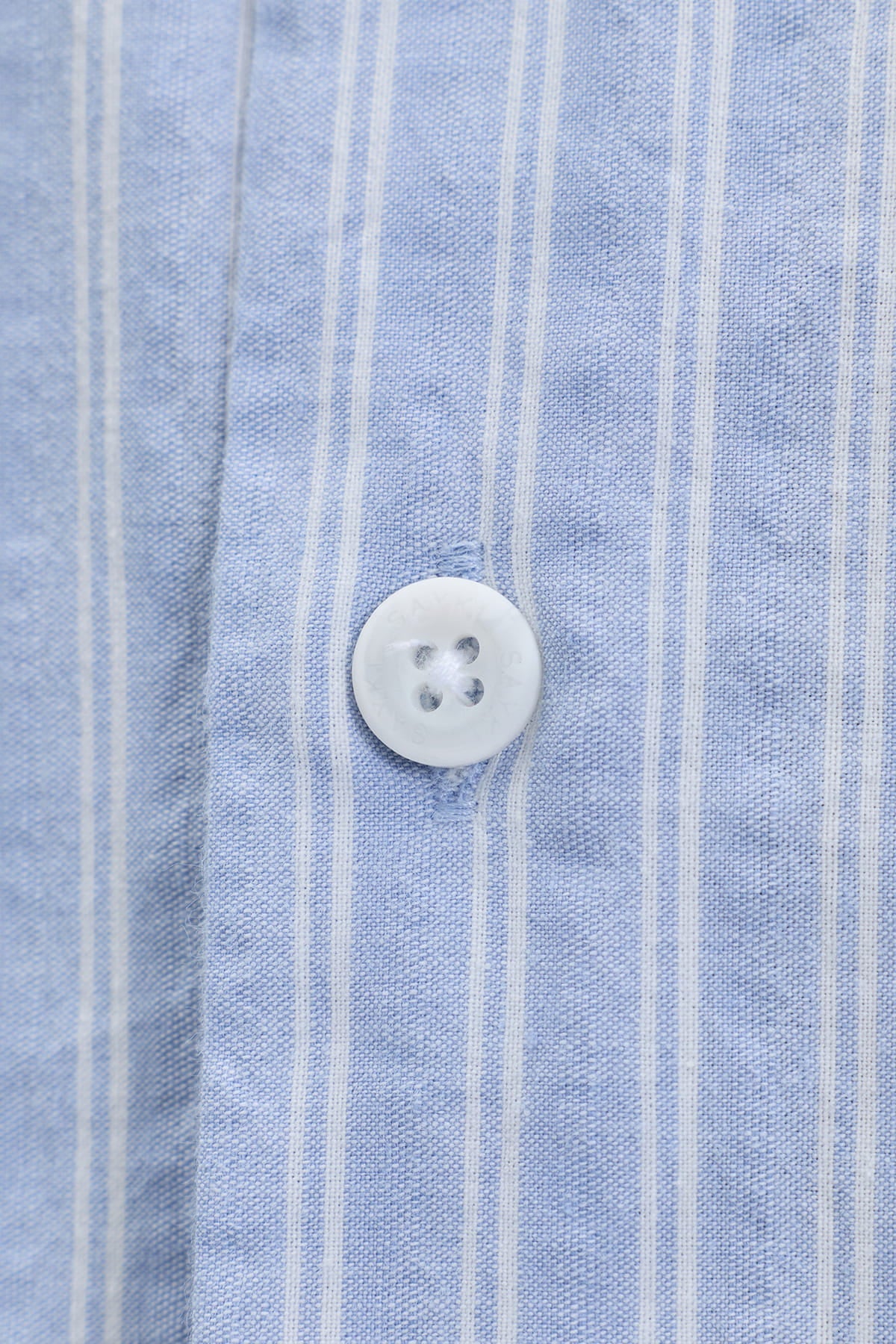 A white four-hole button on a comfort fit blue striped cotton smart casual shirt with vertical stripes