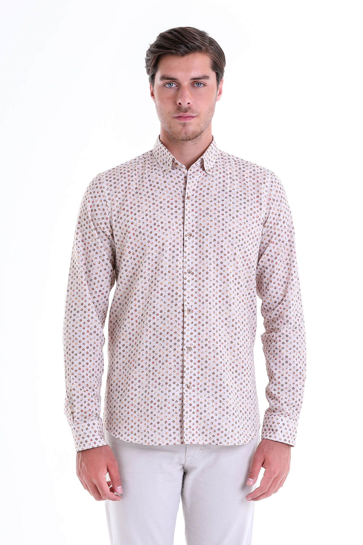 A man wearing a light-colored, long-sleeved button-up shirt with a subtle all-over pattern of small dark dots.