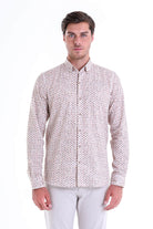A man wearing a light-colored, long-sleeved button-up shirt with a subtle all-over pattern of small dark dots.