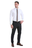 A man wearing a white comfort fit french cuff tuxedo shirt made of 100% cotton with dark formal trousers and brown shoes