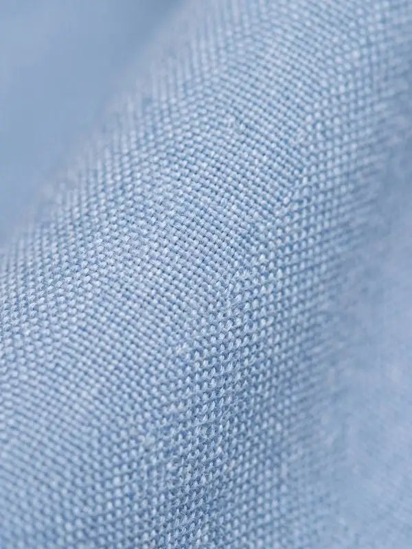 Macro close-up of light blue cotton blend dress shirt fabric showing the fine woven texture