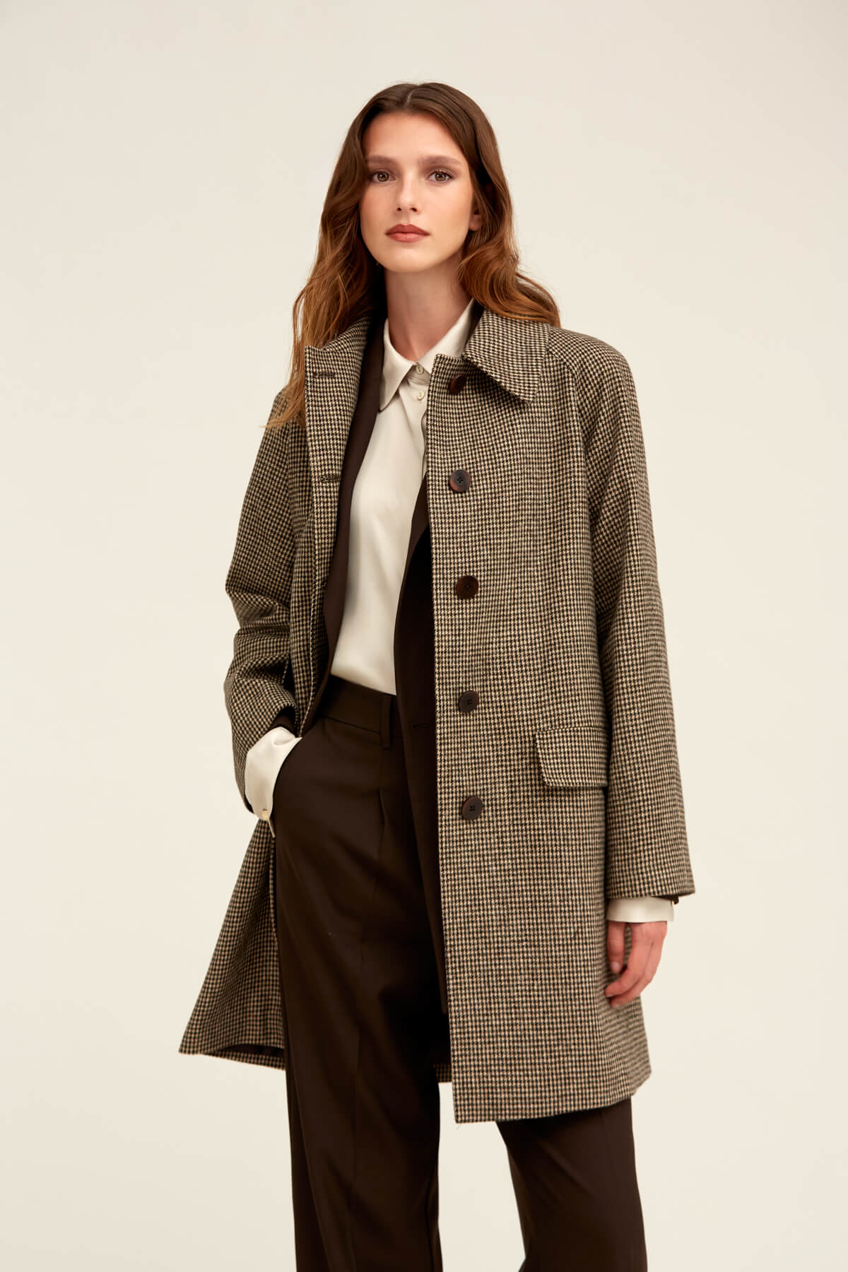 A stylish brown and black houndstooth wool overcoat with a classic collar, front button closure, and flap pockets.