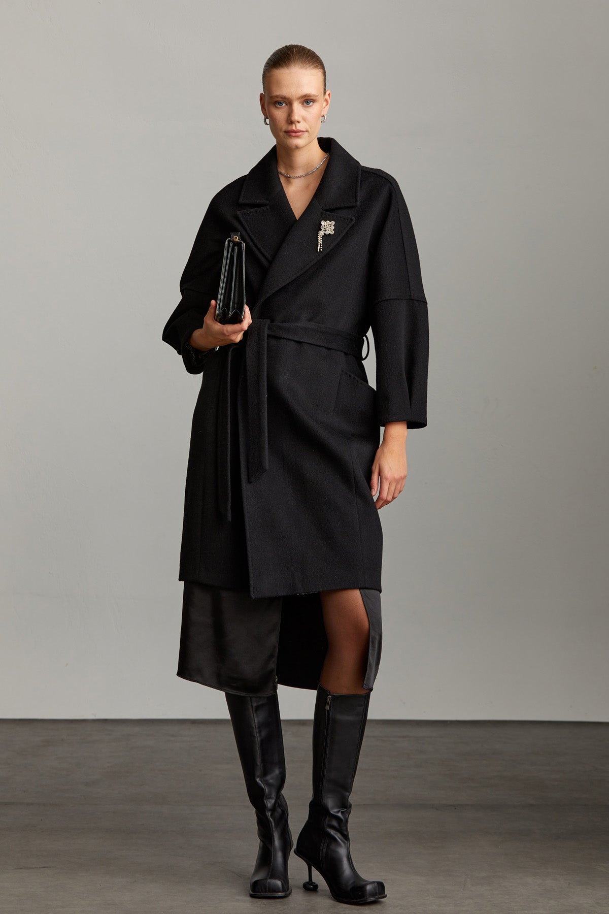 Black belted coat with a structured collar and three-quarter length sleeves.