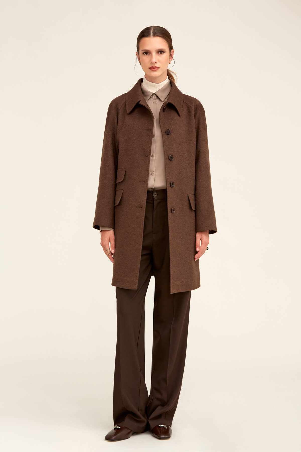 Brown trench coat with a classic collar, buttoned front, and flap pockets.