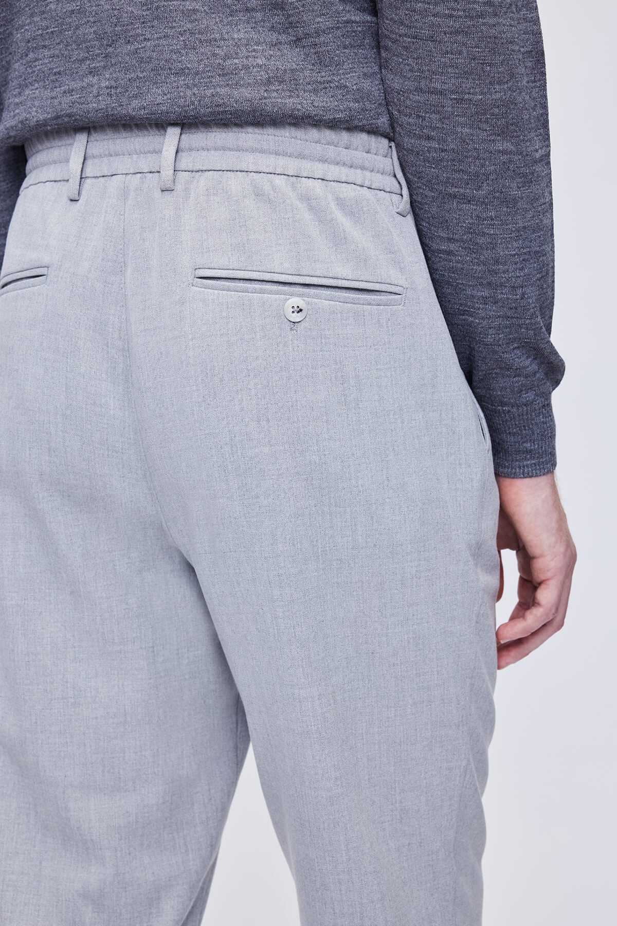 Light gray textured trousers with a subtle woven pattern and a buttoned back pocket.