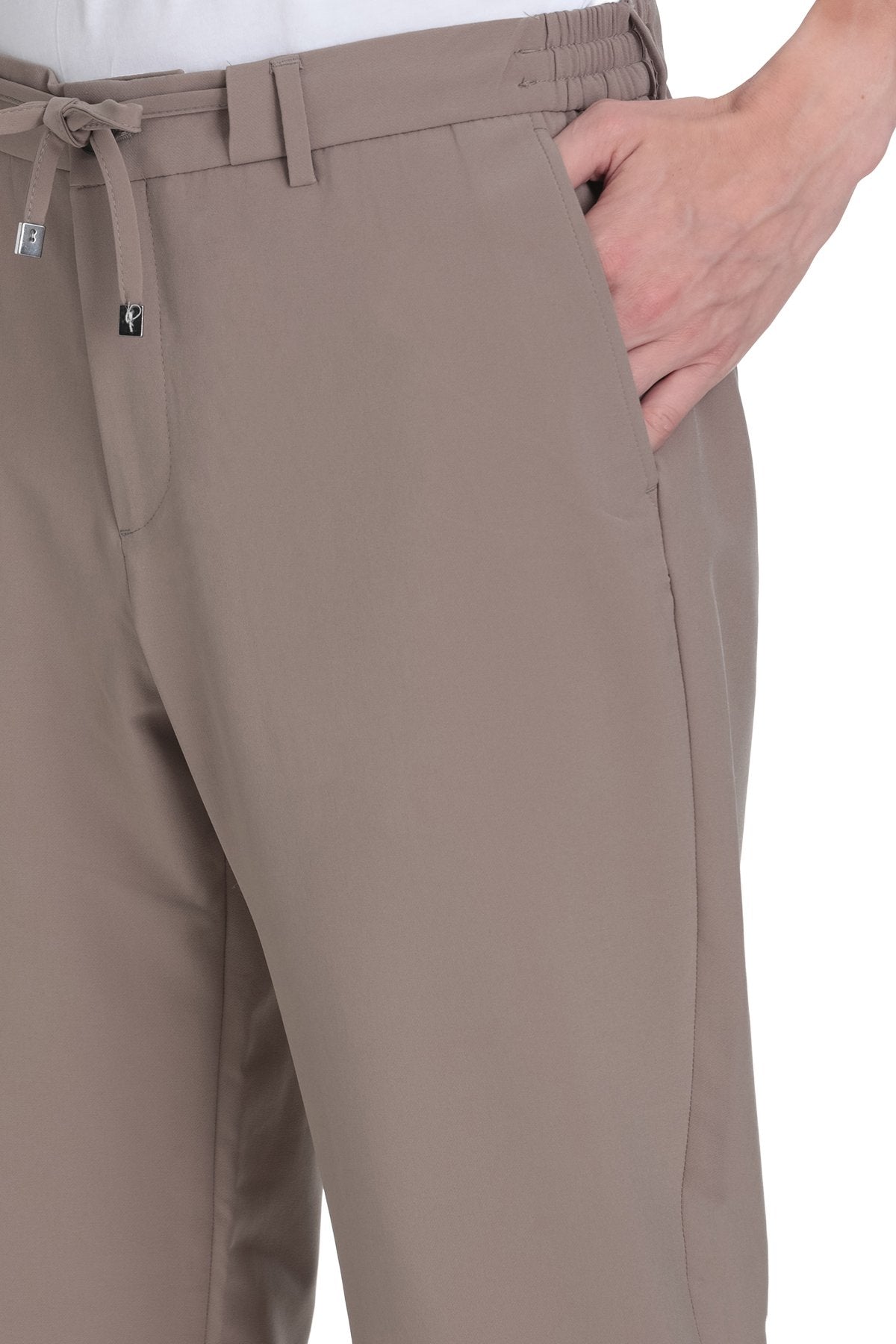 Beige chino trousers with an elastic waistband and drawstring, featuring a sleek, tailored design.