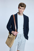 A tan woven straw tote bag with a brown leather strap.