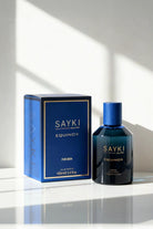 Deep blue glass bottle of sayki equinox men’s eau de parfum 100 ml with matching cap beside navy-blue box