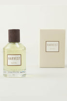 A clear glass bottle of sayki harvest men’s eau de parfum 100 ml with dark wood cap and pale yellow liquid beside cream box