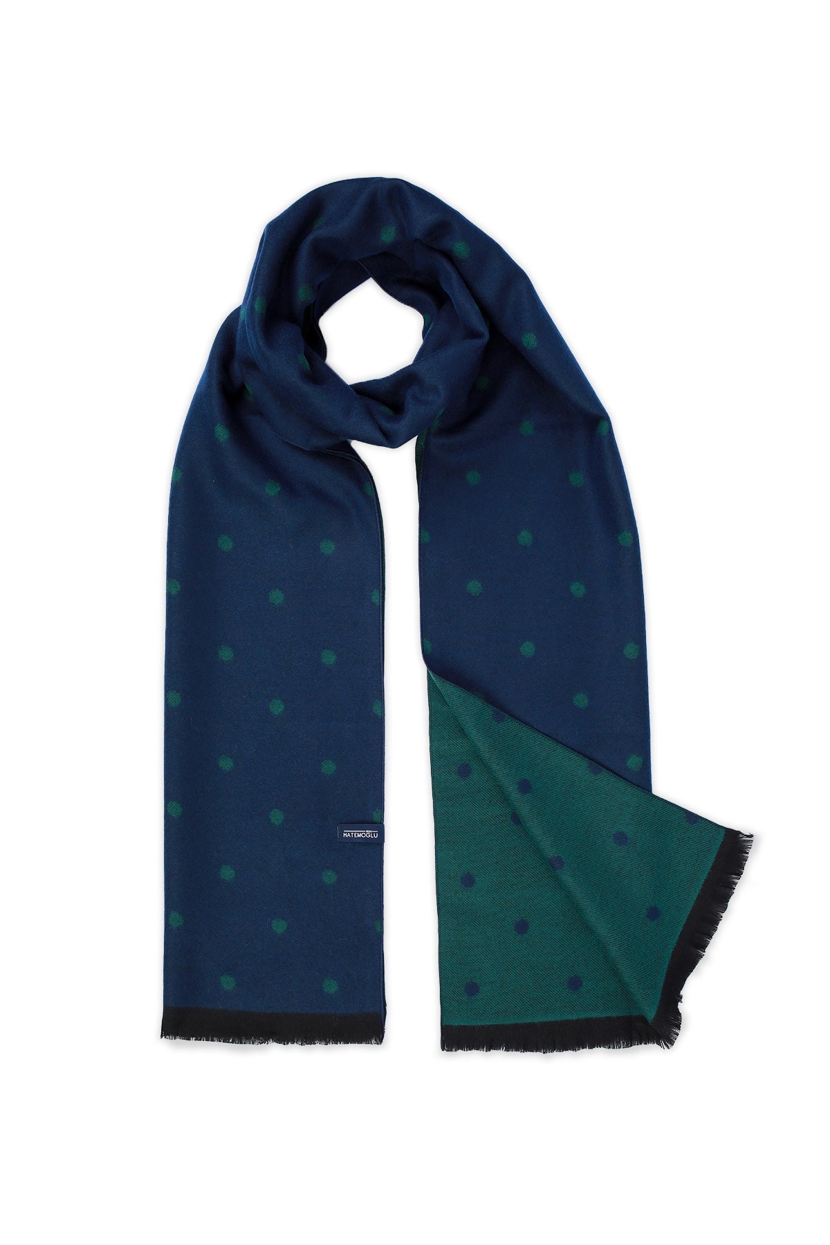 A navy blue scarf with a subtle green polka dot pattern and a contrasting emerald green underside, featuring black frayed edges.