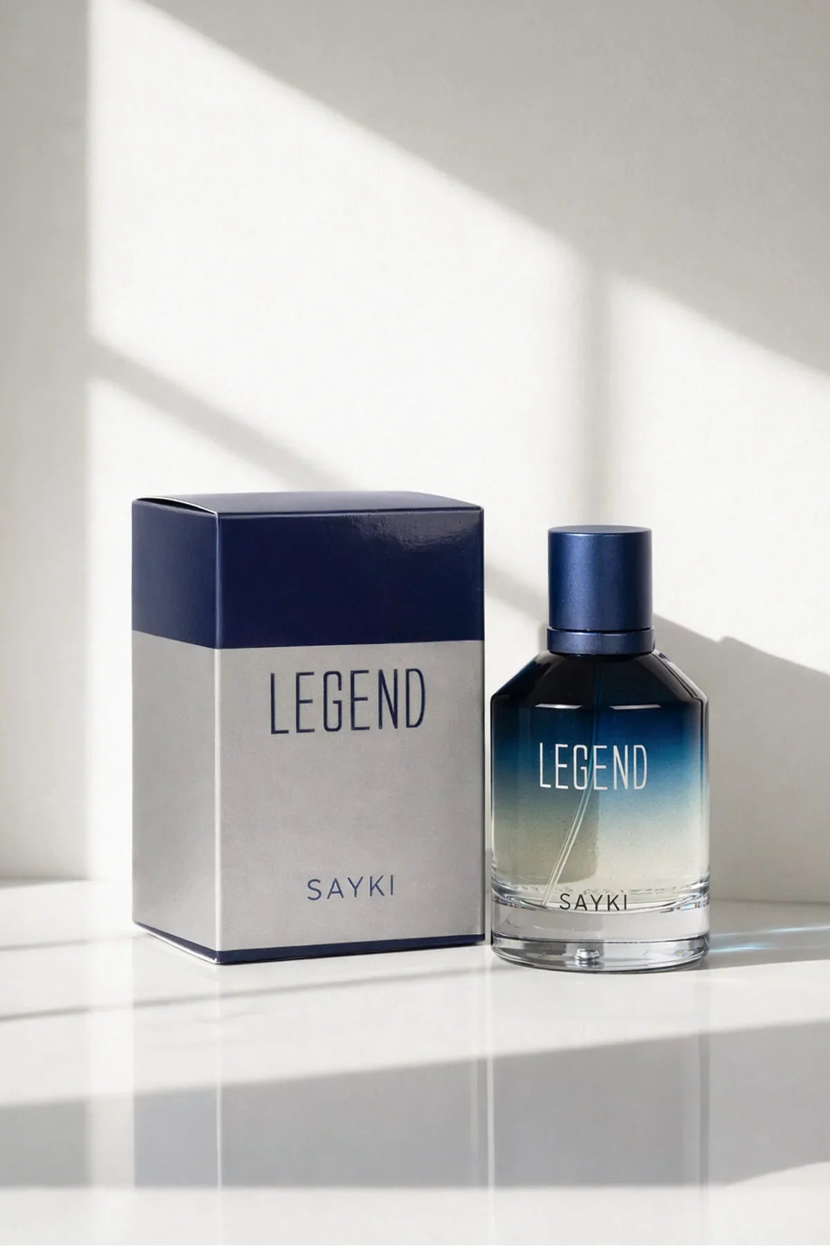 A sleek gradient blue-to-clear glass bottle of sayki legend men’s eau de parfum 100 ml with navy cap and box