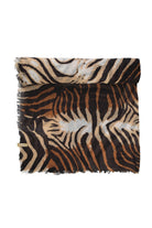 A soft, fringed scarf featuring a bold zebra and tiger stripe pattern in black, tan, and shimmering silver.