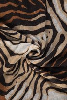 A soft, flowing scarf featuring a bold zebra print with black and tan stripes.