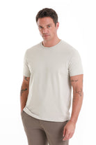A slim-fit, off-white crew-neck t-shirt with a subtle embroidered logo on the left chest.