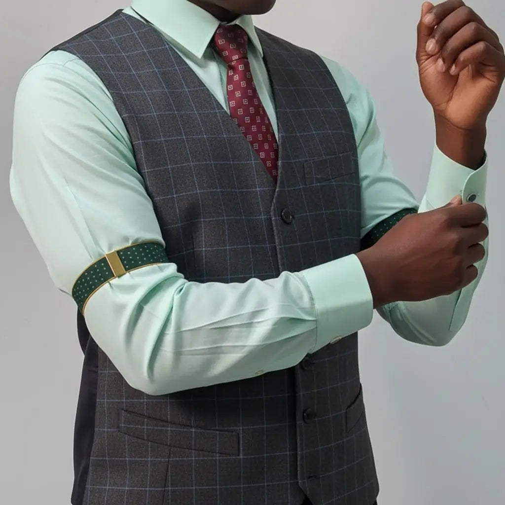 Man wearing a gray checkered vest over a light green shirt with a red patterned tie on a plain background