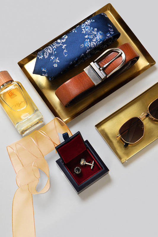 Blue floral patterned necktie in a satin finish, neatly folded and displayed on a gold tray.