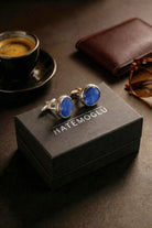 A pair of navy natural stone round cufflinks with blue stones and silver frames in a black hatemoglu box