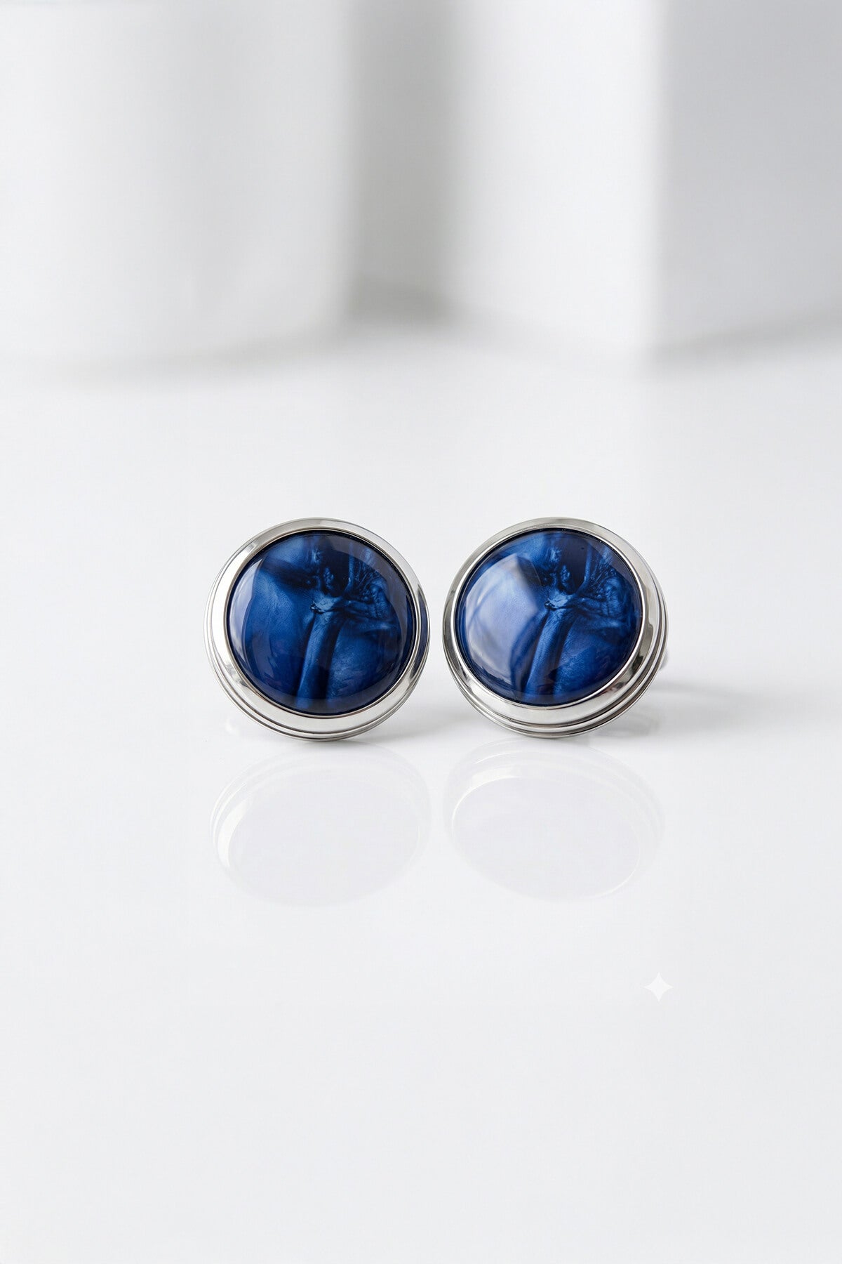 Silver-toned stud earrings with navy natural stone deep blue glossy resin cabochons featuring a swirling pattern