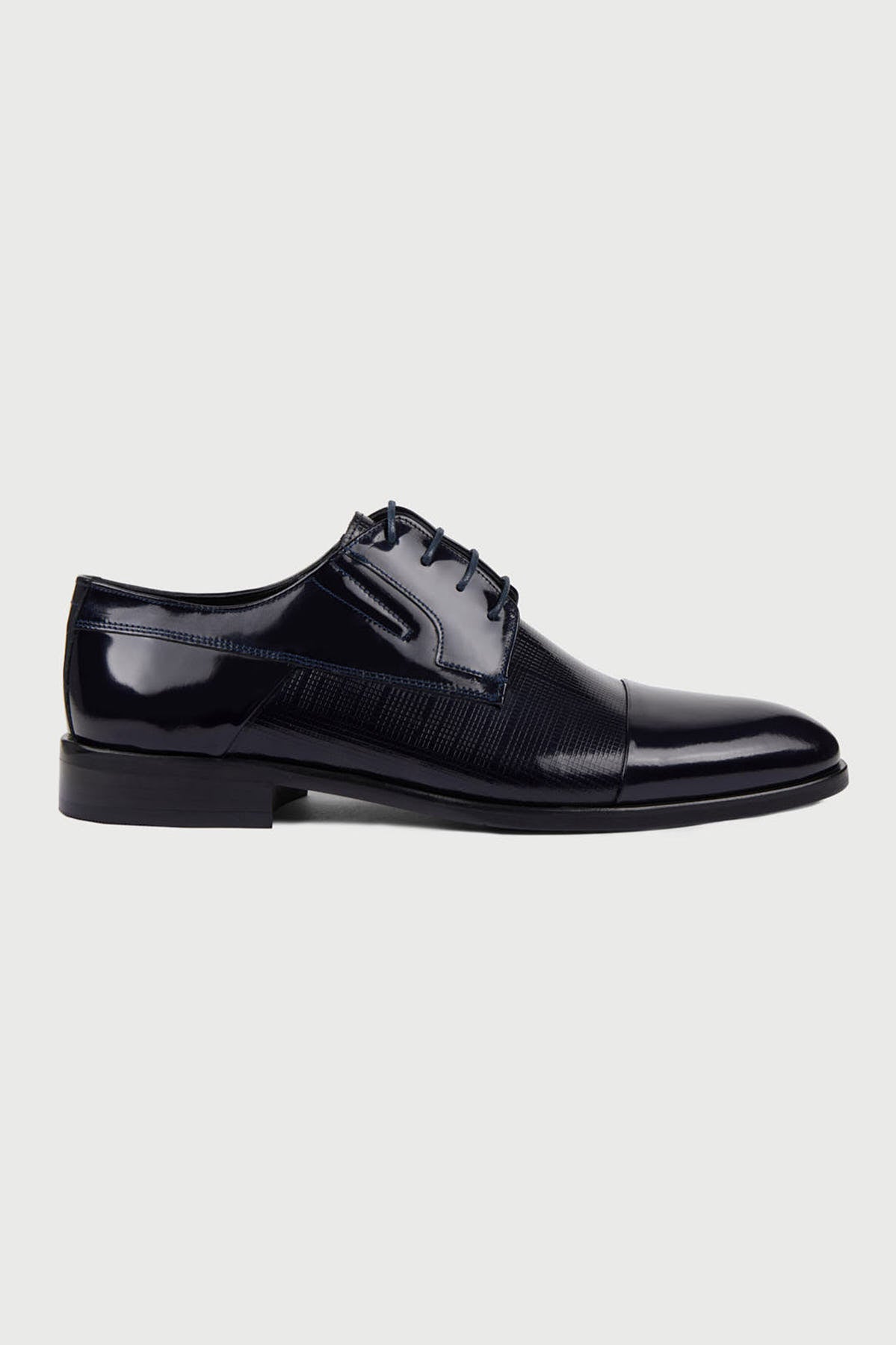 Black patent leather derby shoe with a glossy finish and subtle textured paneling.