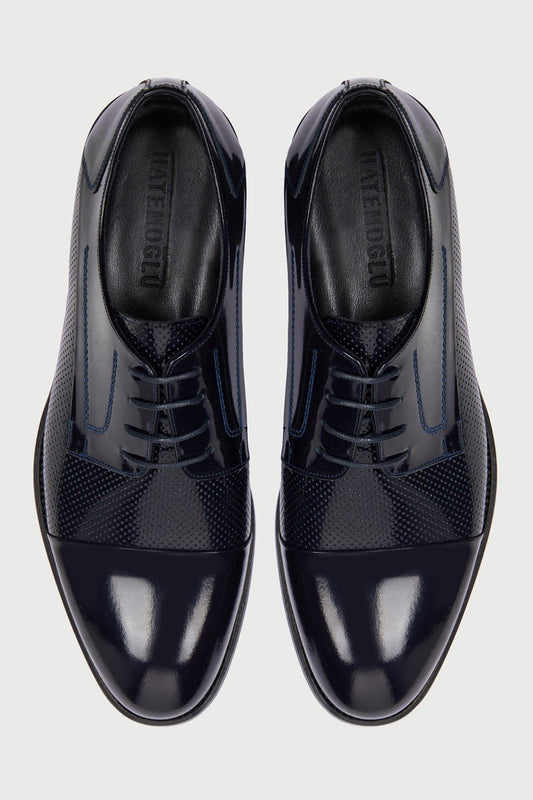Black patent leather and textured suede oxford shoes with blue stitching accents.