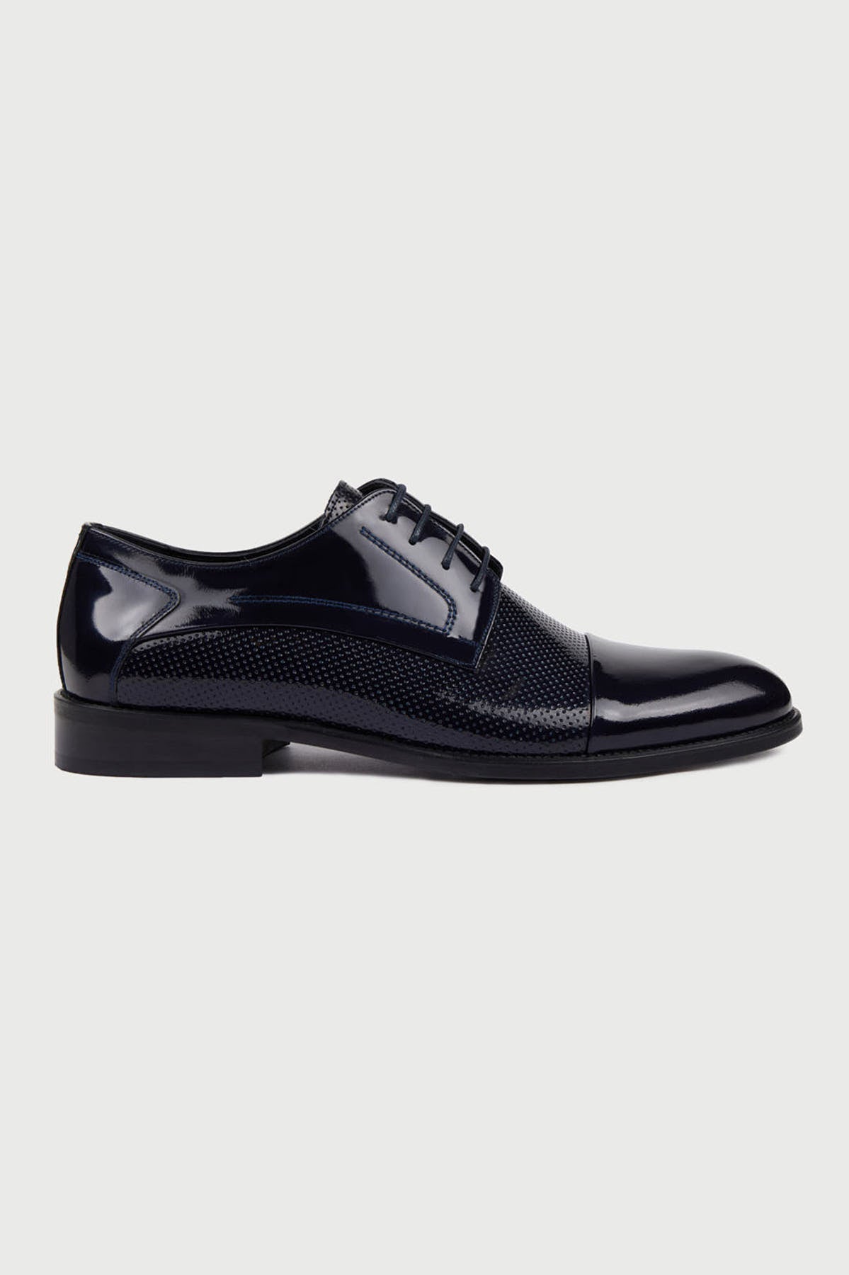 Black patent leather derby shoe with a perforated mesh panel on the side.